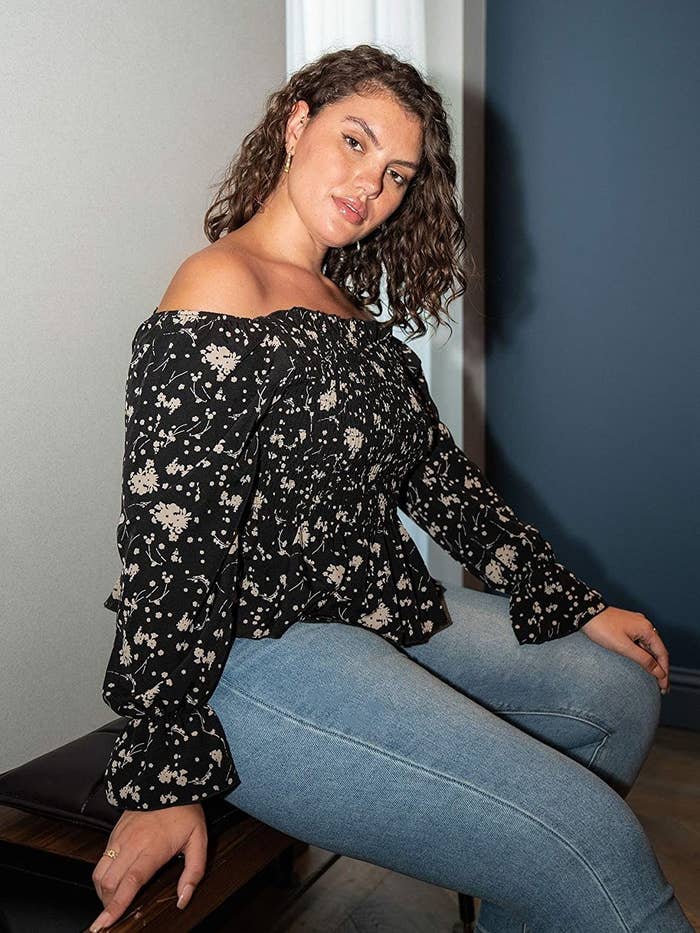 plus size model wearing black off the shoulder top with jeans