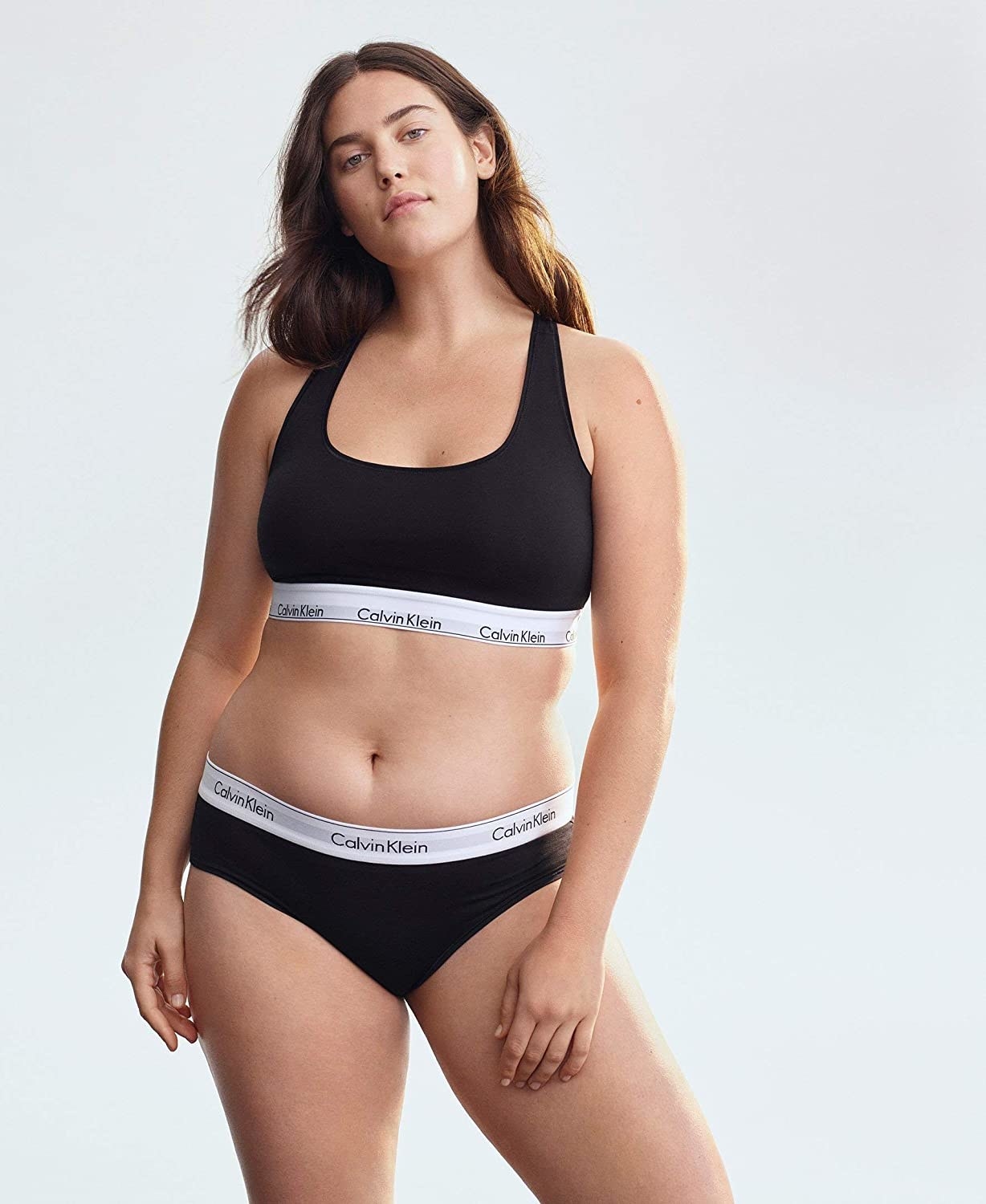 model wearing black bralette with white logo band and matching underwear