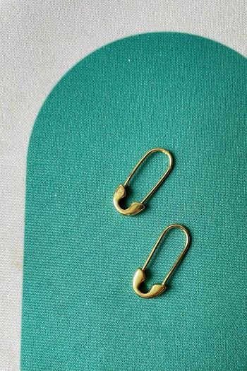 a buzzfeed editor's gold safety pin earrings on a green background