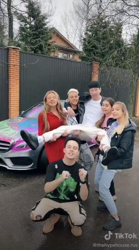 a bunch of tiktokers standing in front of their super nice car and home