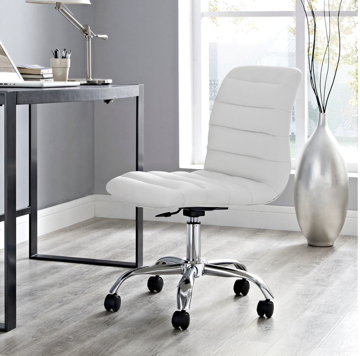 A white armless office chair in front of a desk