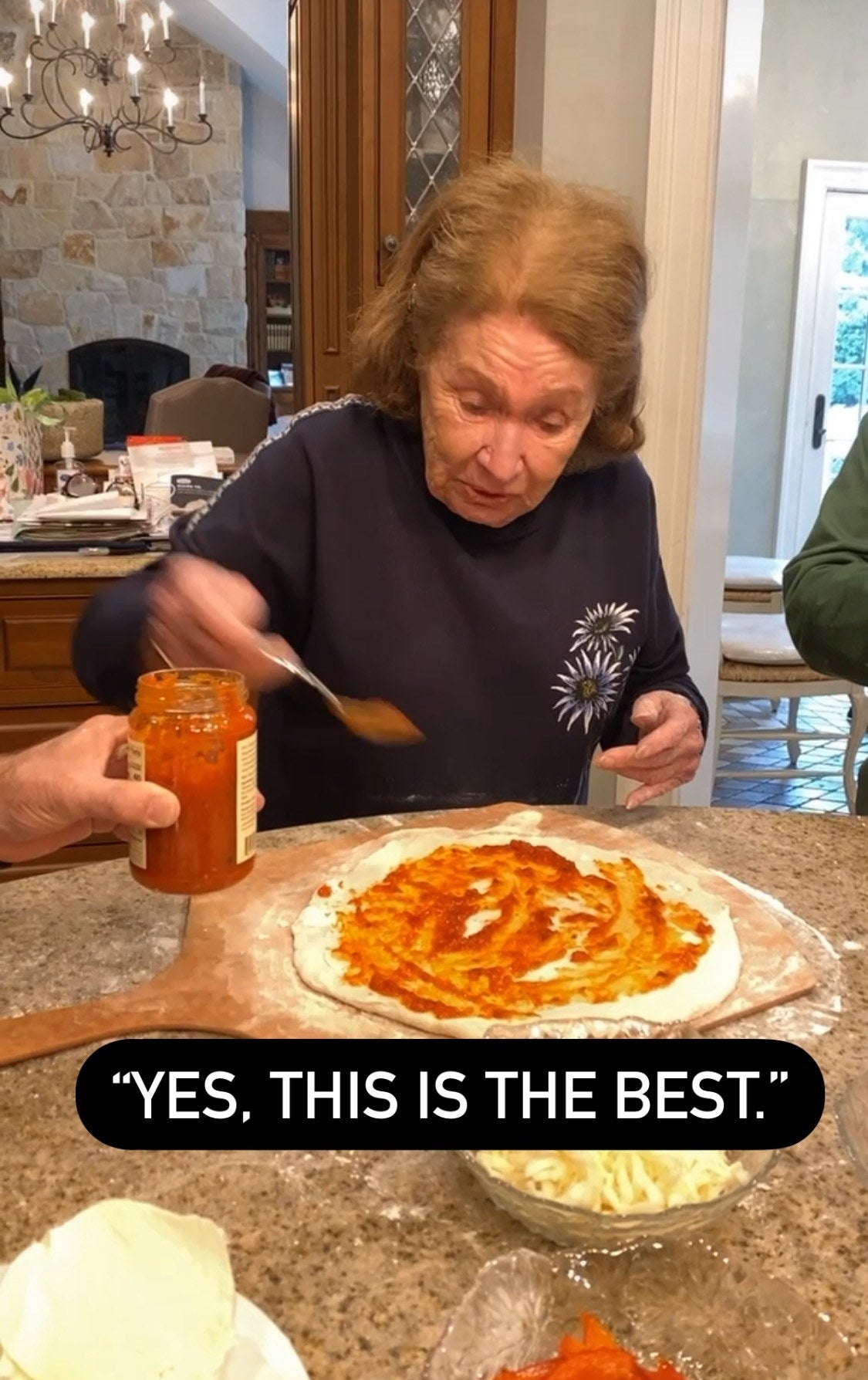 Grandpa putting sauce onto her pizza dough