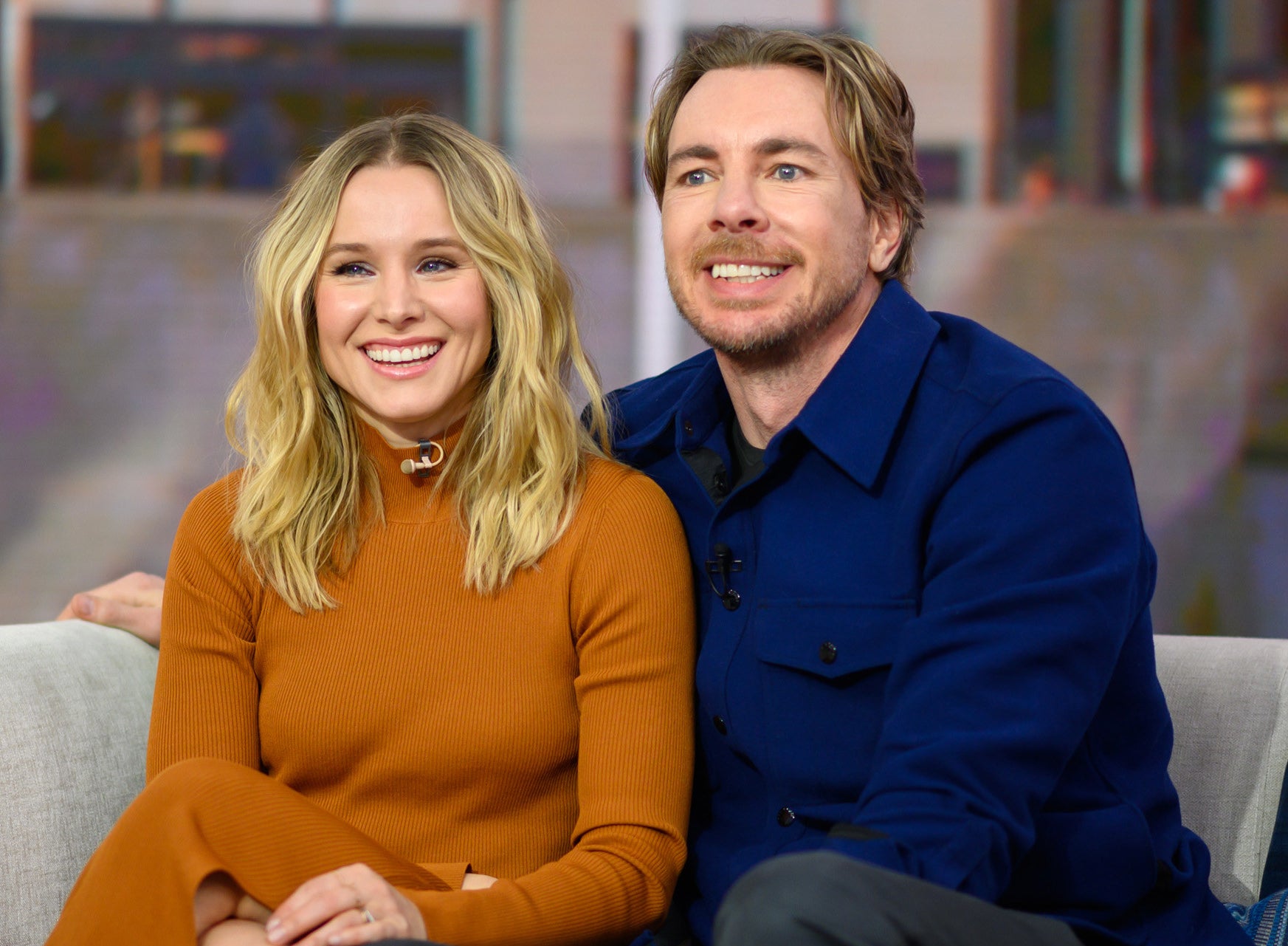 Dax puts his arm around Kristen while they sit on a couch for an interview