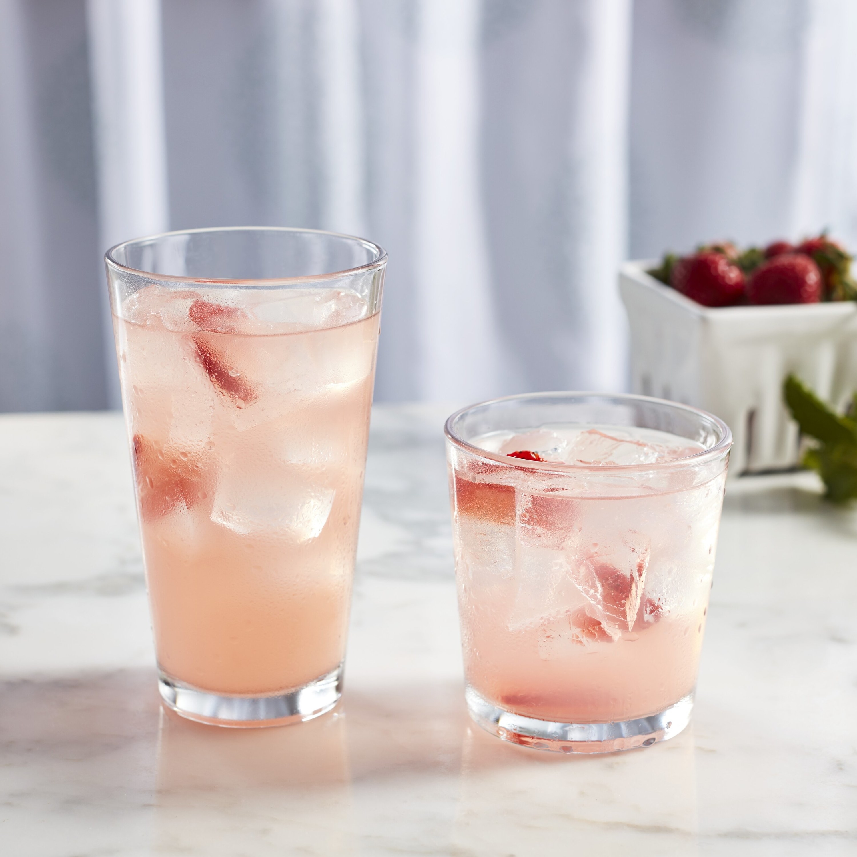 Tall and short glasses with strawberry lemonade inside