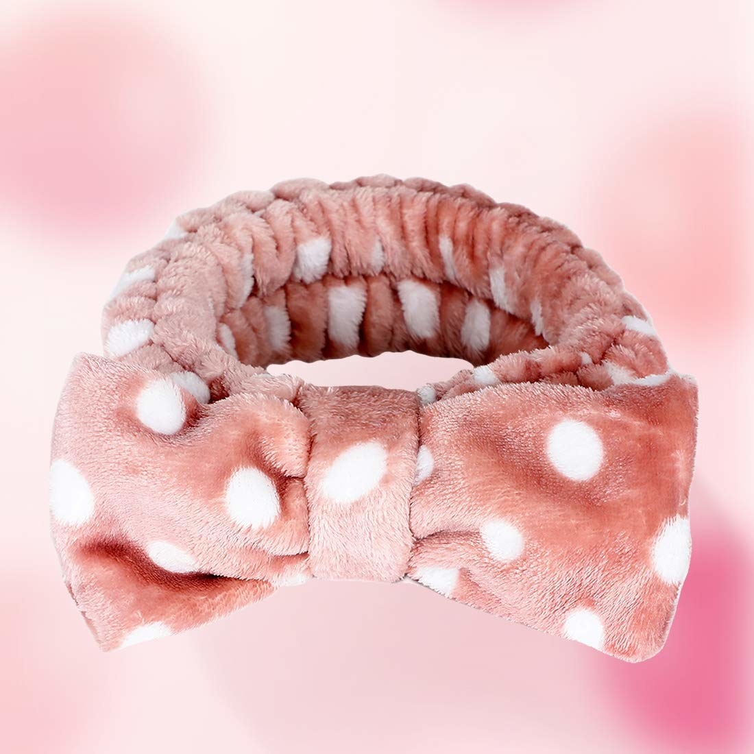 A pink headband with a white polka dot design