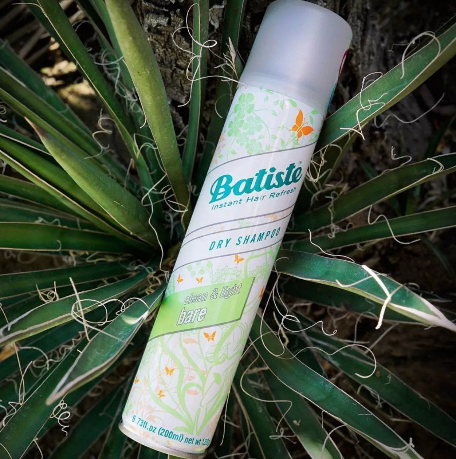 the bottle of dry shampoo laying on a plant