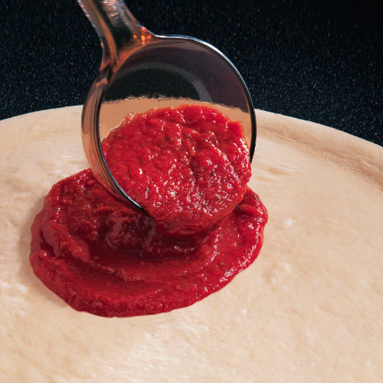 sauce being spread onto pizza dough