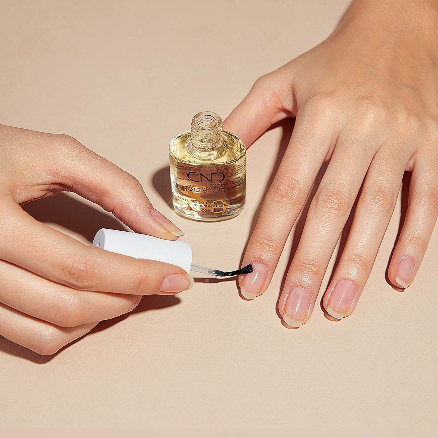 A person applying the oil to their cuticles