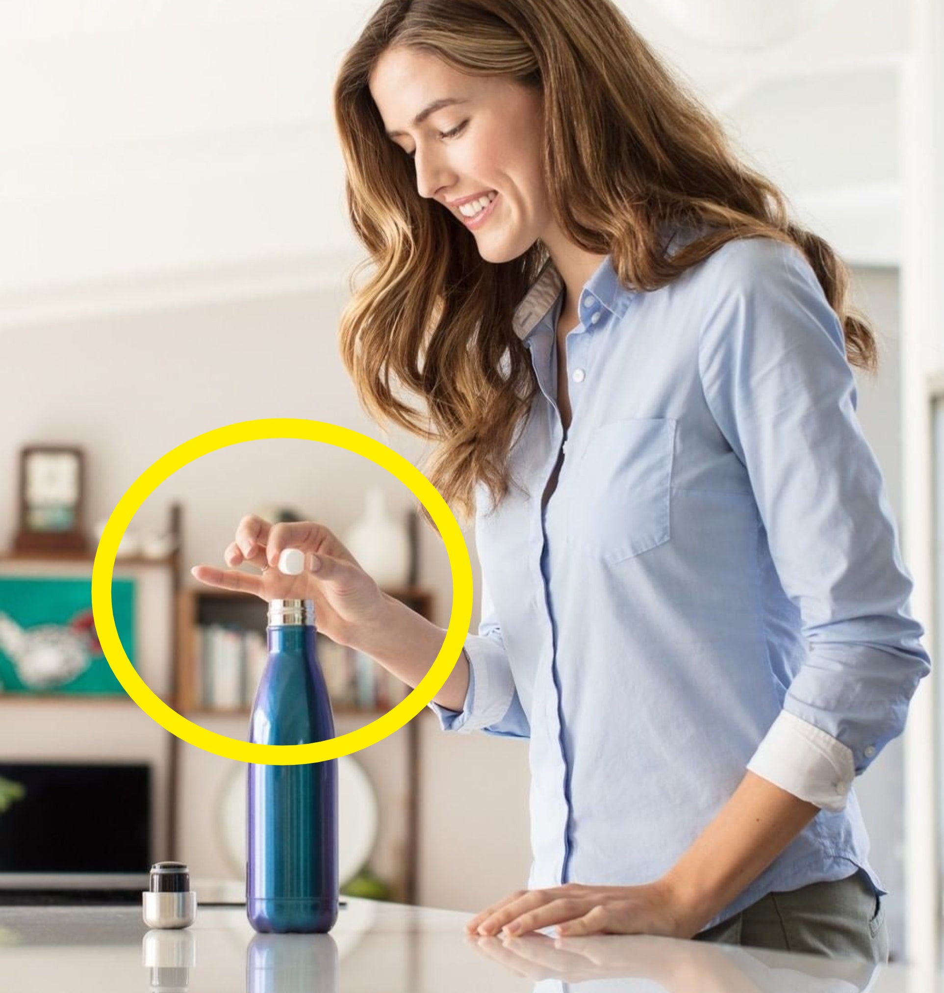 A person dropping the tablet into a water bottle