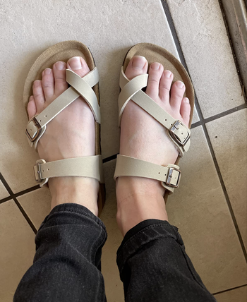 Reviewer wearing light beige strappy buckled sandals with cork-like soles 