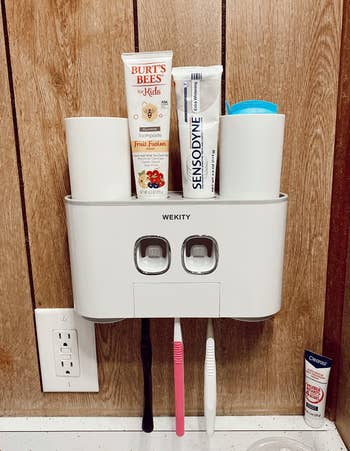a reviewer's white wall mounted toothbrush holder