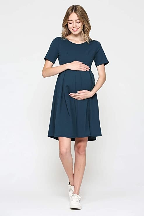 model wearing midi style dress with short sleeves and pleats above the belly area