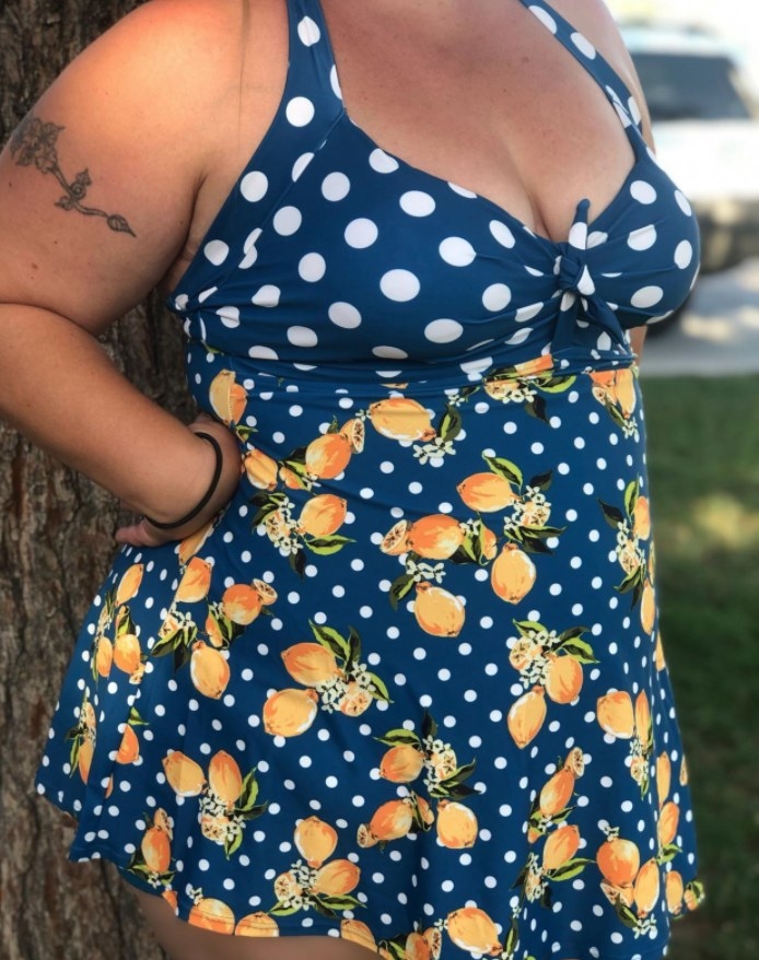 A reviewer wearing the suit in the orange polka dot print 