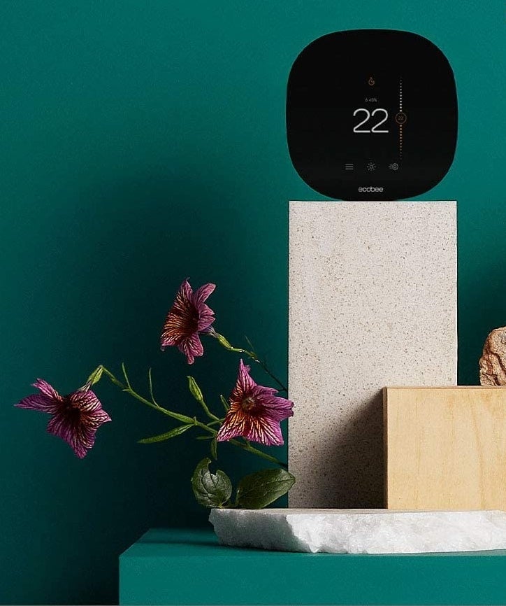 The thermostat sitting on a decorative box next to some flowers 