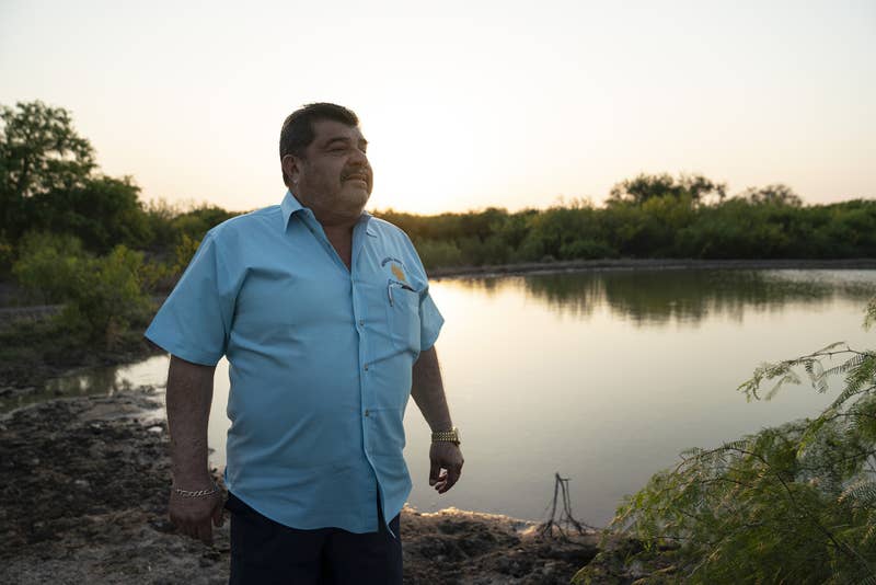 Ociel Mendoza in front of a shallow pond on his ranch at sunset
