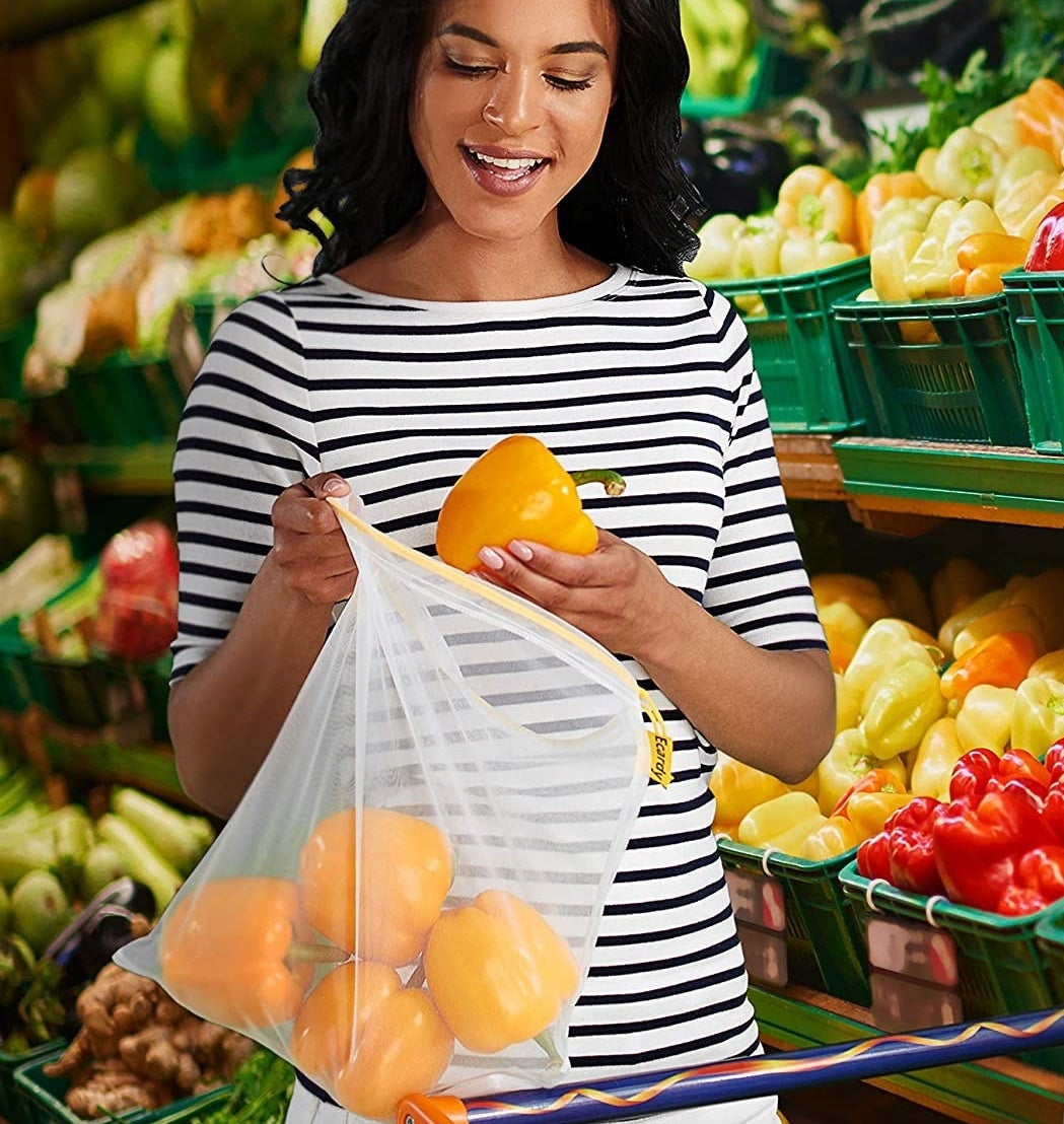 A person putting peppers into the reusable mesh produce bag 