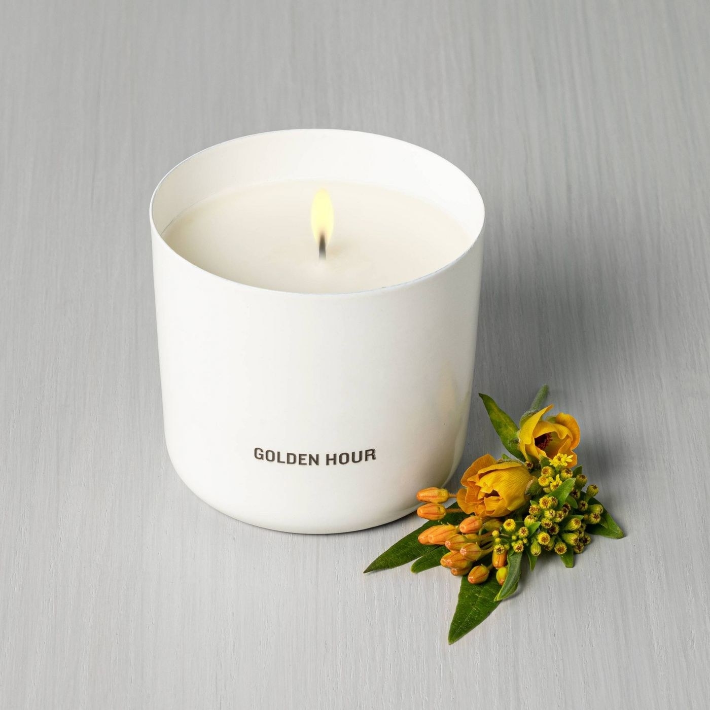 white ceramic container with &quot;golden hour&quot; on the front and lit candle inside