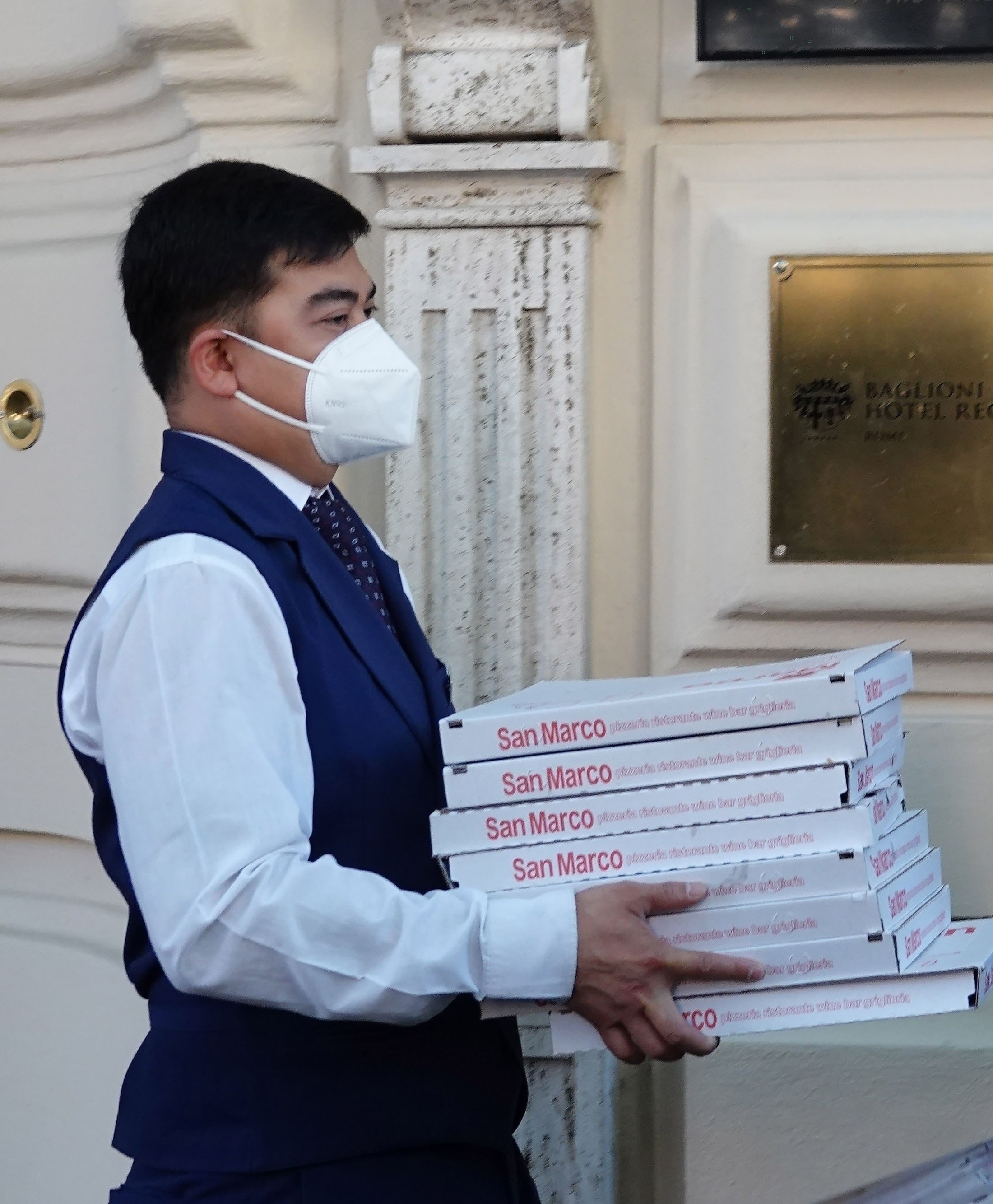 A man holding several boxes of pizza