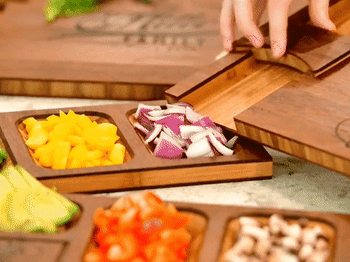 Gif of someone chopping on the board and using the divots and attached pieces to push the prepped food off the board  