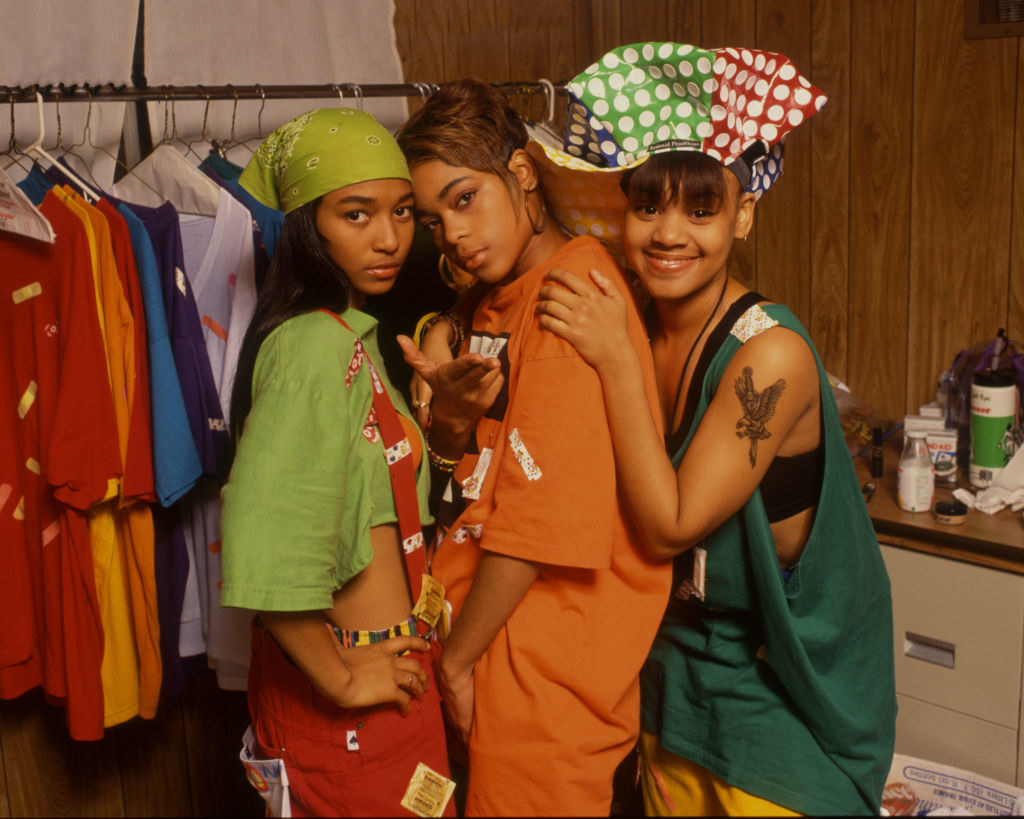 Rozonda &quot;Chilli&quot; Thomas, Tionne &quot;T-Boz&quot; Watkins, and Lisa &quot;Left Eye&quot; Lopes taking a portrait with condoms taped to their outfits, UK, 1992