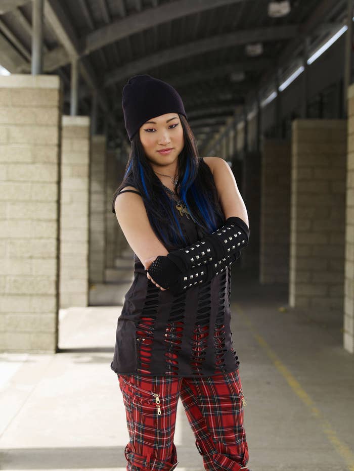 Long muscle shirt with shreds with a tank underneath, baggy plaid pants with lots of zippers, and long wrist cuffs/fingerless gloves with studs and a beanie