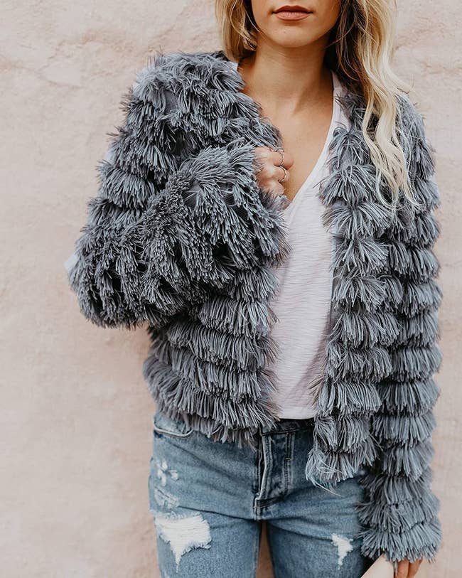 close up of model wearing the gray shaggy parka over a white tee and distressed jeans