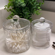 Two clear glass jars with lids, both are filled with ear swabs and cleaning pads 