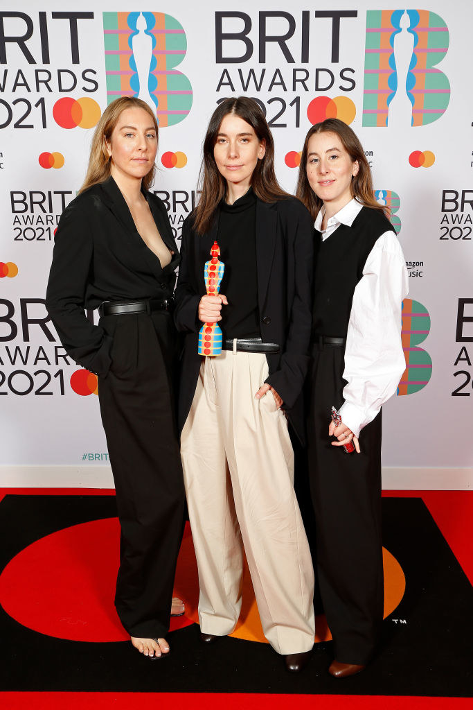 (L-R) Danielle Haim, Este Haim, and Alana Haim of Haim pose in pant suits in the media room with the International Group award