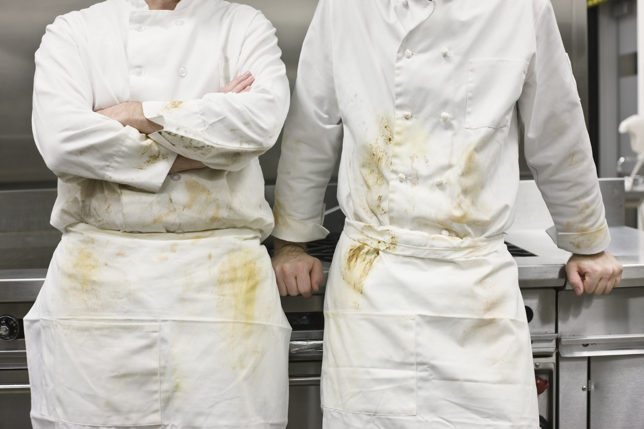 Dirty chefs leaning against stove