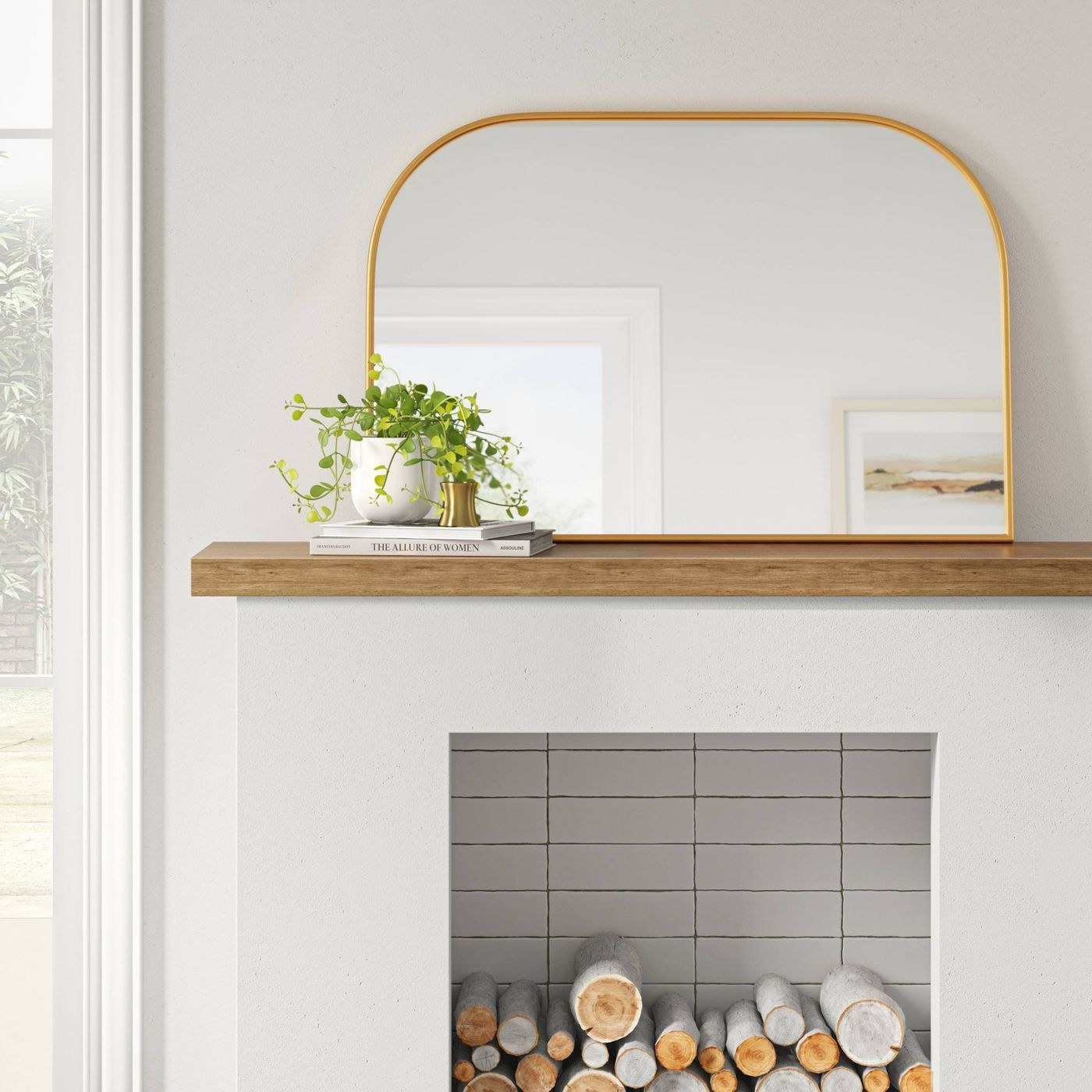 arch-shaped mirror with gold trim sitting on a mantle above a fireplace