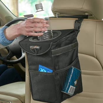 Waterproof trash holder hung from passenger seat back. Person places empty water bottle inside. 