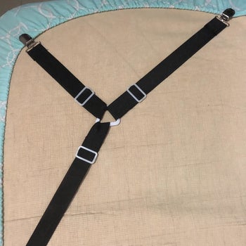 a reviewer image of the three-sided sheet clips holding a fitted sheet on the underside of a mattress 