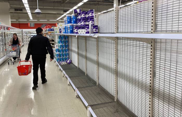 A man walking through a store with empty shelves