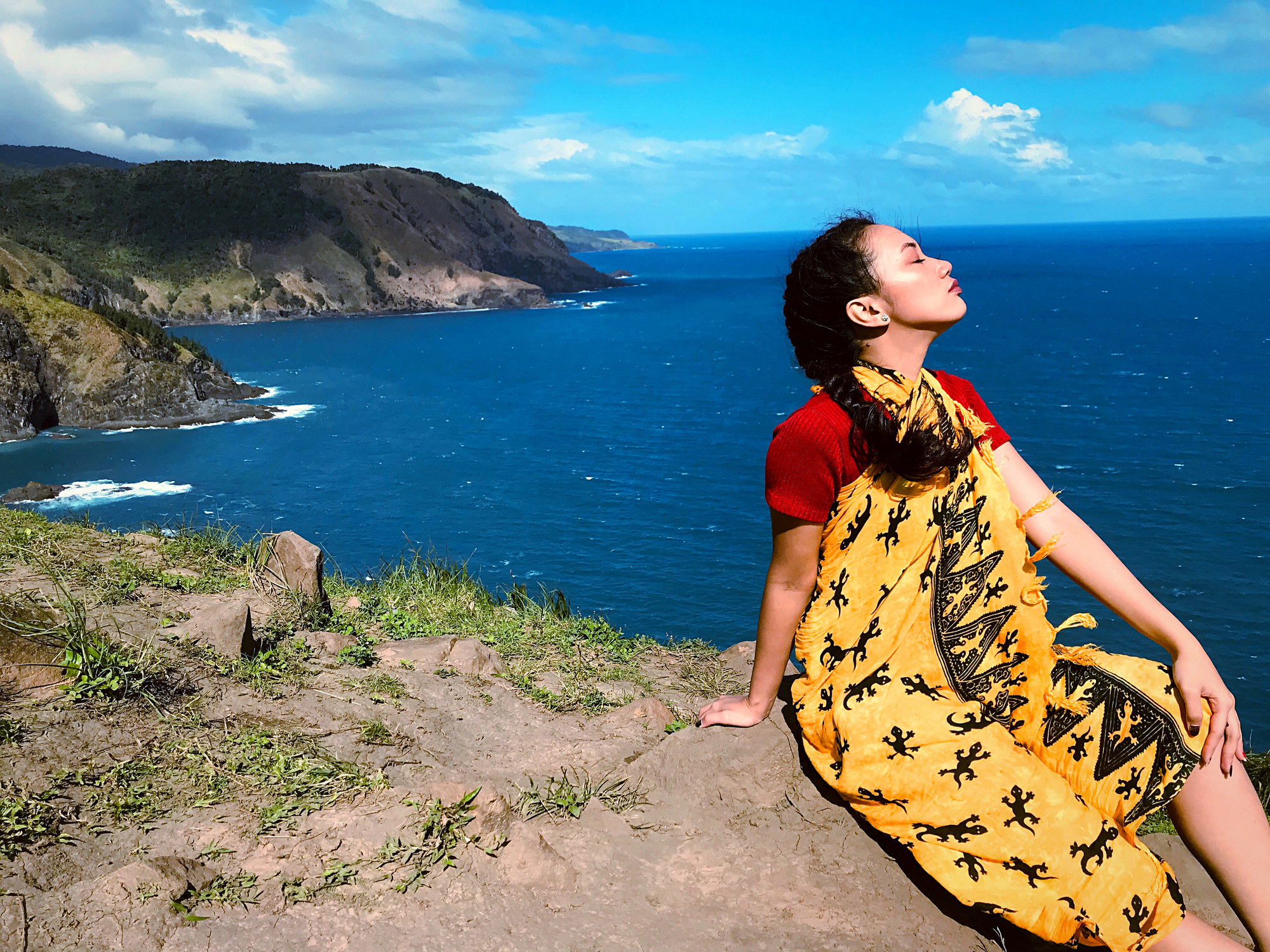 Woman on seaside cliff in yellow wrap dress