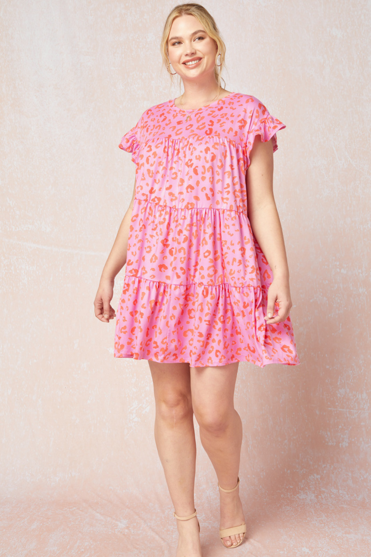 model wearing a short sleeve tiered loose pink dress with orange cheetah spots on it