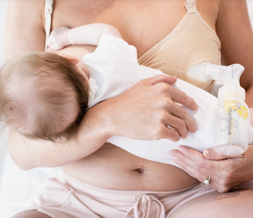 baby nursing through a sports bra-like bra while pumping through one breast