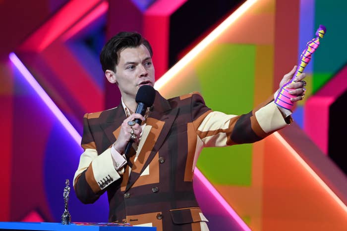 Harry holds up his award while giving his speech