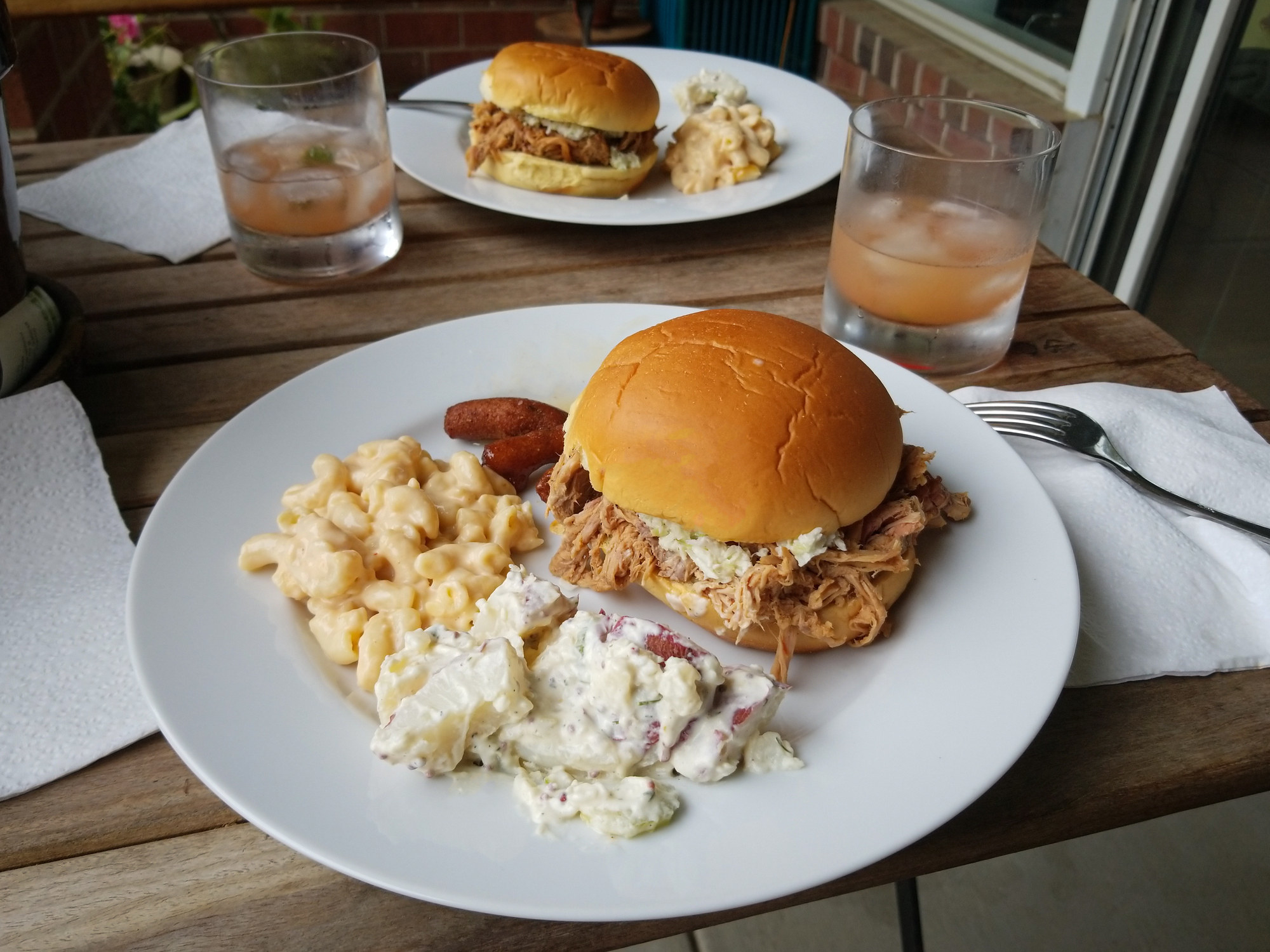 A pulled pork sandwich with slaw and sides of potato salad and mac 'n' cheese.
