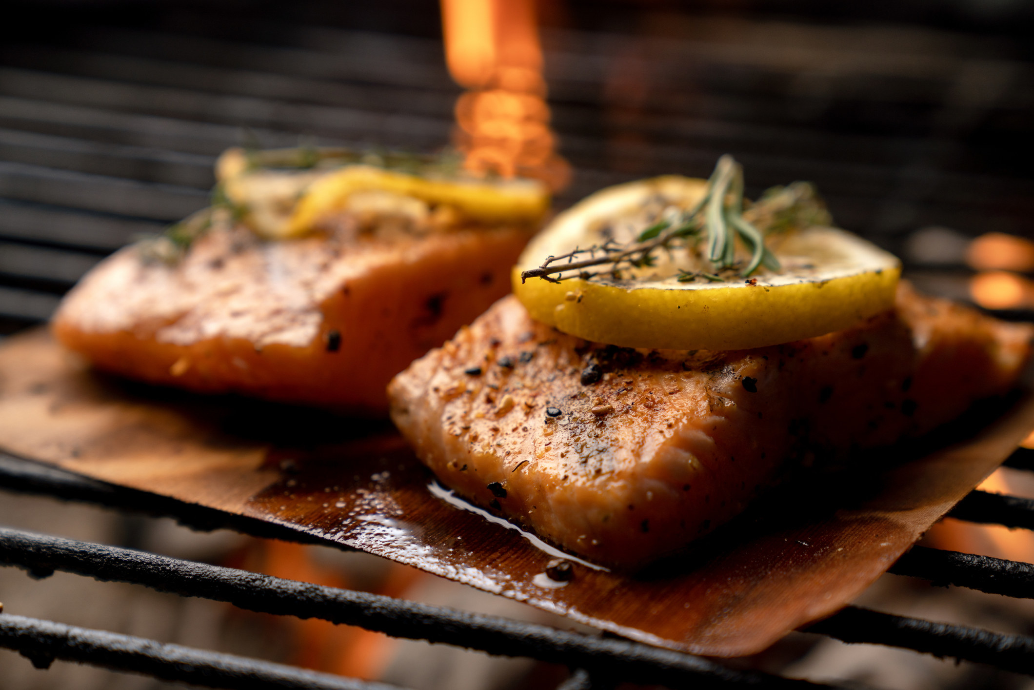 Two pieces of salmon on a wooden plank.