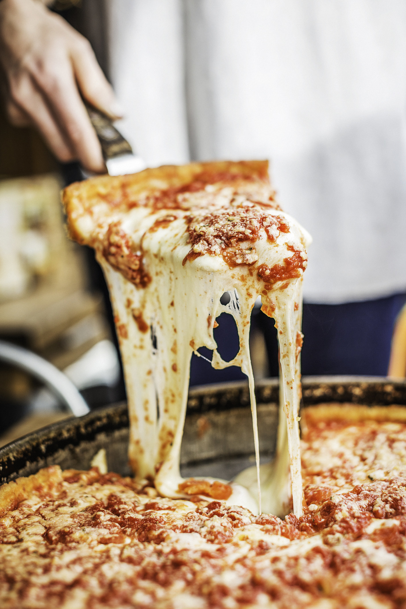 Serving a slice of cheesy, deep dish pizza.