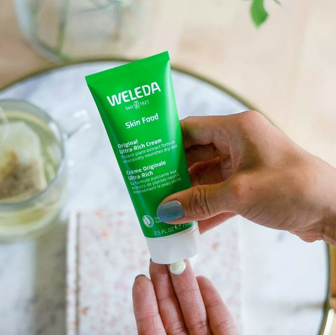 hand squeezing out Weleda cream