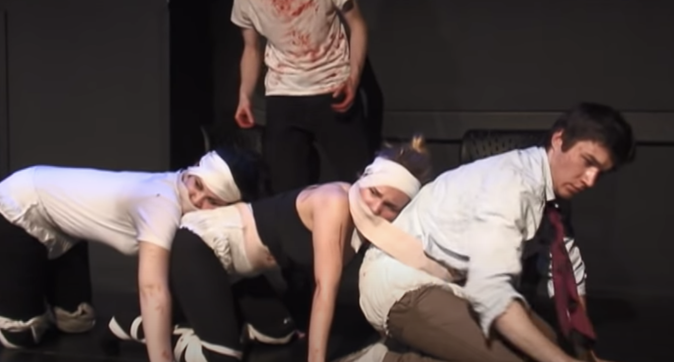 People onstage with their heads tied to others&#x27; butts