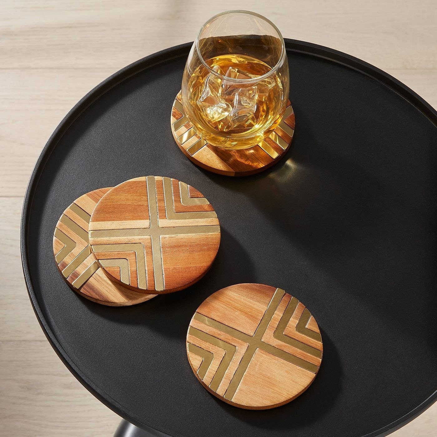 four round wood coasters with gold detail on a black tray