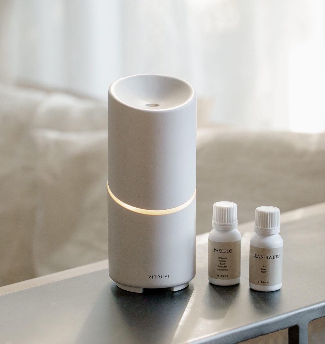 A cordless electronic diffuser next to two bottles of essential oils