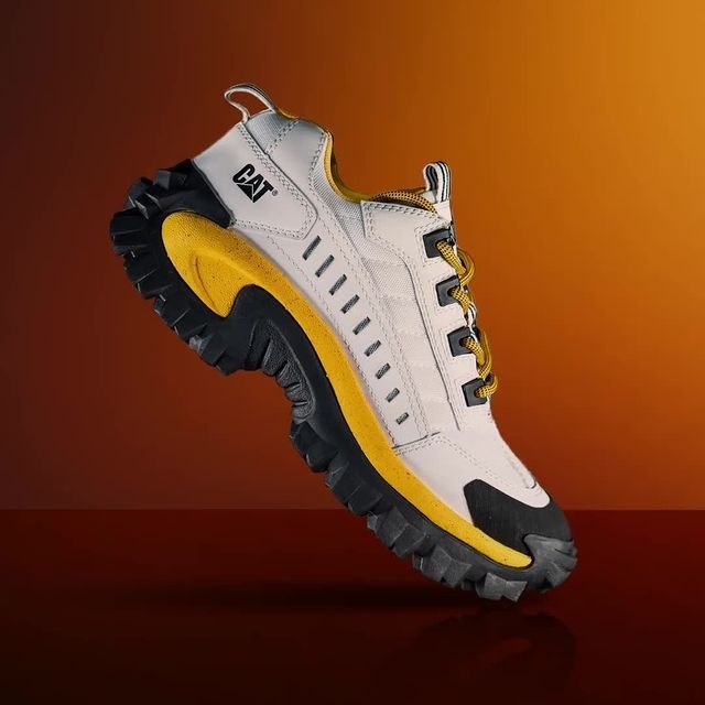 a chunky white sneaker with black and yellow accents and a thick tread on the bottom