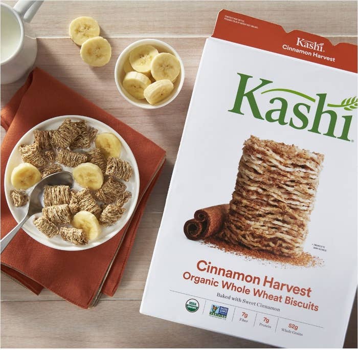 A box of Kashi Cinnamon Harvest cereal next to a bowl of the cereal with sliced bananas 