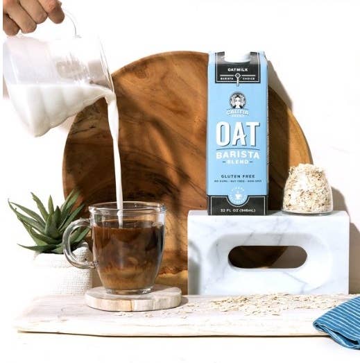 A model pouring Califia Farms oat milk into a cup of coffee