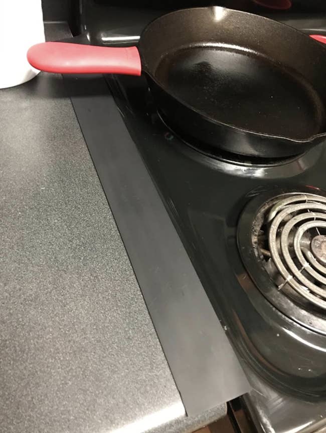 A reviewer photo of a black silicone stove gap filler in between the stove and the counter
