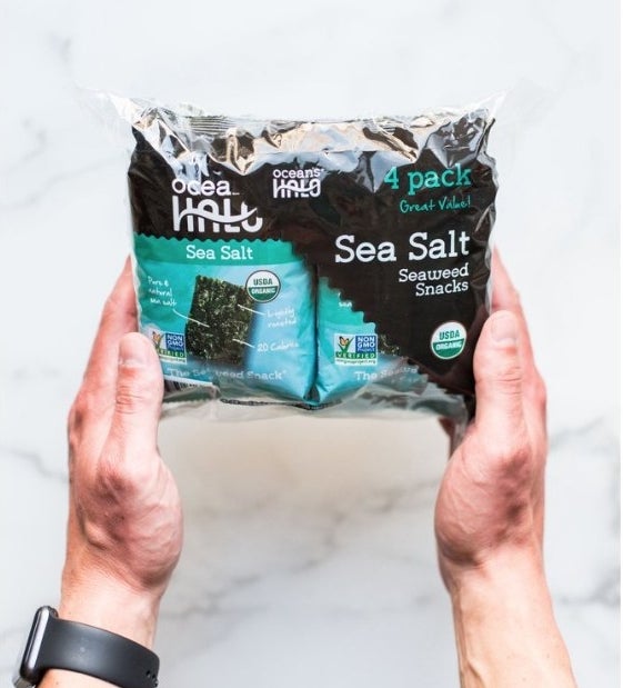 A model holding a 4-pack of Ocean&#x27;s Halo seaweed snack