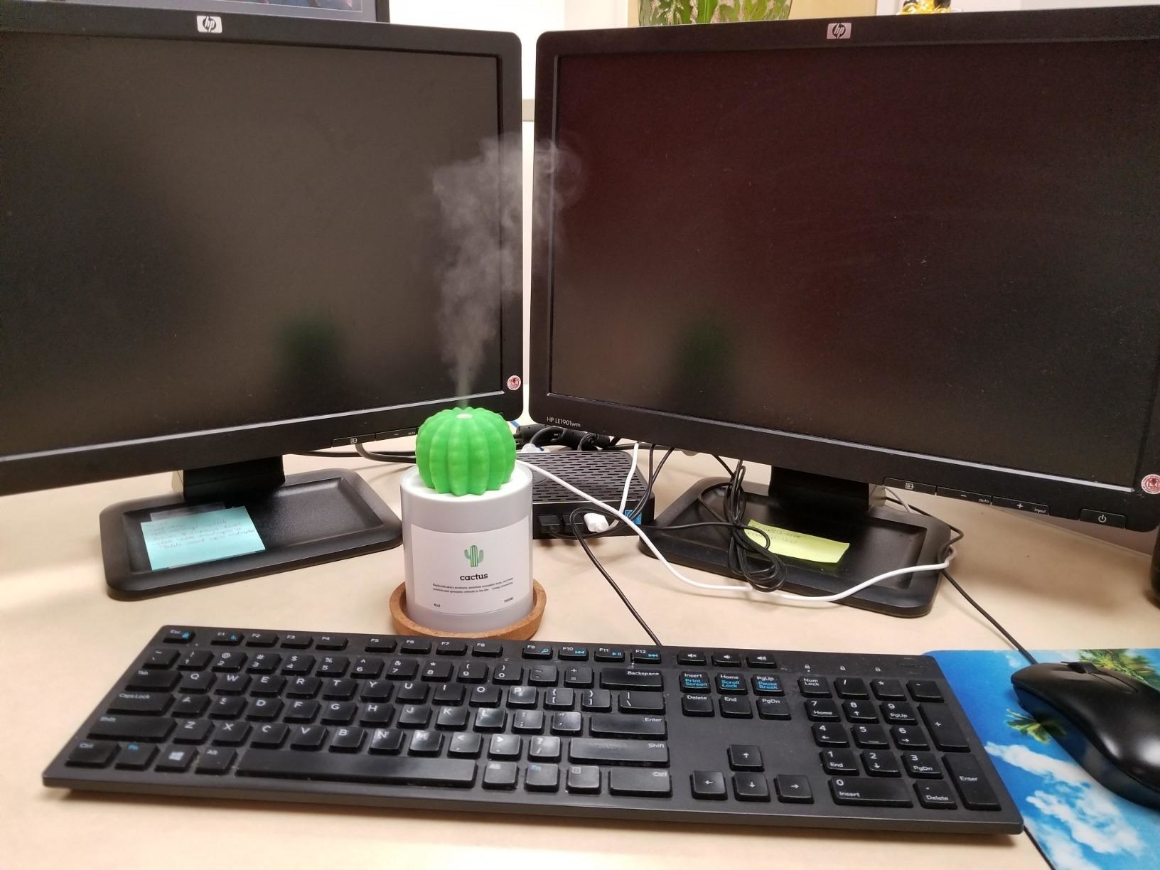 the small humidifier sat between a reviewer&#x27;s computer screens releasing its mist 